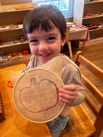 A child proudly holding a Montessori puzzle